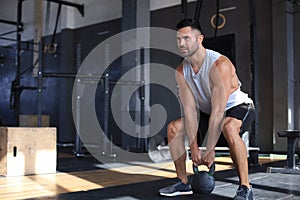 Fit and muscular man focused on lifting a dumbbell during an exercise class in a gym