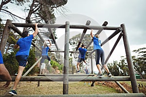 Fit people climbing monkey bars in bootcamp