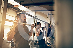 Fit people doing pull ups together at the gym