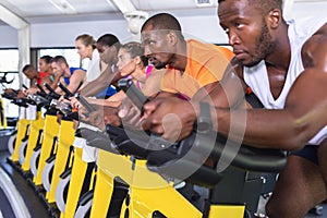 Fit people exercising on exercise bike in fitness center