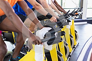 Fit people exercising on exercise bike in fitness center