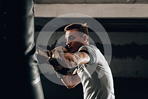 Fit professional boxing man kicking at punching bag