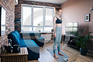 Fit redhead young woman doing stretching warm-up exercises for muscle at home.