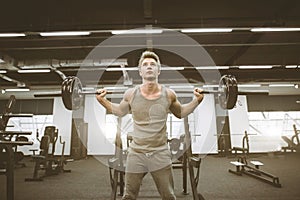 Fit and ripped man lifting weights in the gym. Gym lifestyle concept. Athletic man exercising with barbell at gym