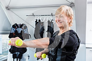 Senior lady staying fit with dumbbell exercise in wireless ems gym photo