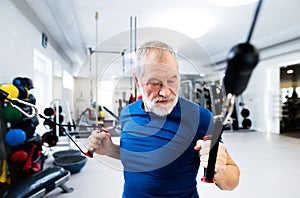 Fit senior man in gym working out with weights.