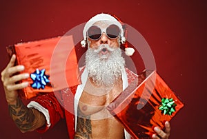 Fit senior man having fun wearing Santa Claus clothes and holding Christmas presents