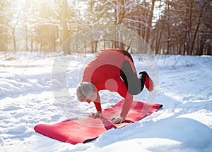 Fit senior man having outdoor yoga practice in winter at snowy forest