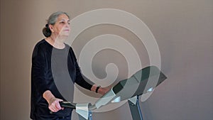 Fit senior woman at home on treadmill doing cardio work out.