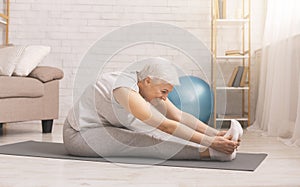 Fit senior woman stretching at home, free space