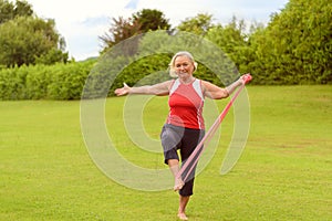 Fit senior woman using resistance bands with leg