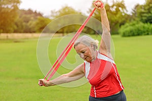 Fit senior woman using resistance bands outside