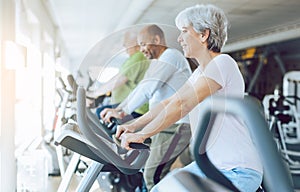 Fit seniors on stationary fitness bikes in the gym