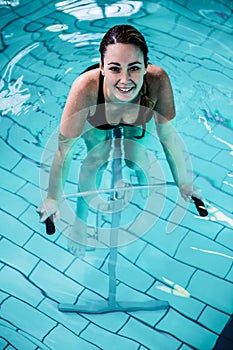 Fit smiling woman cycling on a swimming bike