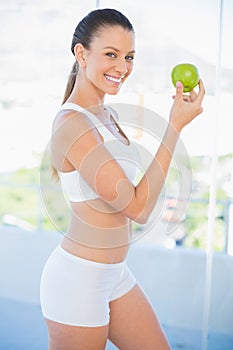 Fit smiling woman holding green apple