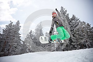 Fit snowboarder jumping with snowboard on ski terrain