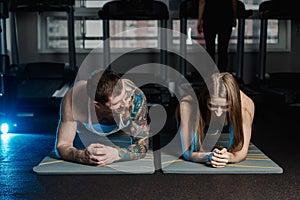 Fit sportive man and woman doing plank core exercise training back and press muscles concept gym sport sportsman fitness