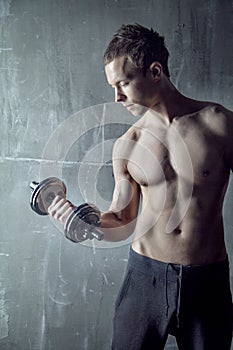 Fit sportive muscular man with dumb-bell in hand