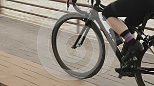 Fit sportive woman rides bicycle on cycle promenade. Motivated pro cyclist is cycling road bike on quay, doing cardio workout, pre