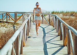 Fit sports woman in sport clothes on ocean coast running