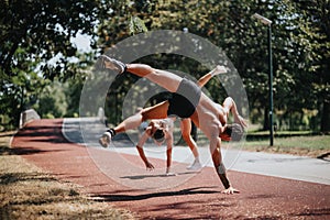 Fit sportspeople practice together in a sunny park doing cartwheels, showcasing their athleticism and inspiring a