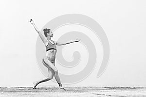 Fit sporty active girl in fashion sportswear doing yoga fitness exercise in front of gray wall, outdoor sports, urban