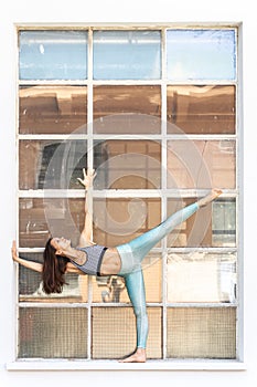 Fit sporty active girl in fashion sportswear doing yoga fitness exercise in front of gray wall, outdoor sports, urban