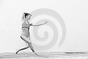 Fit sporty active girl in fashion sportswear doing yoga fitness exercise in front of gray wall, outdoor sports, urban