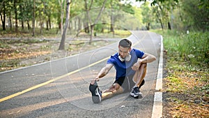 Fit and sporty Asian man stretching his legs on the street, warming up before running