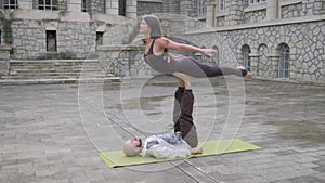 Fit sporty couple practicing acro yoga with partner together on mat, performing front plank bird pose, young man holding flying wo