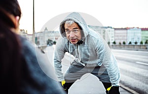 A fit couple runners stretching outdoors on the streets of Prague city.