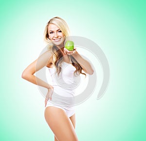 Fit and sporty girl in white underwear. Beautiful and healthy woman eating apple over green background. Sport, fitness, diet, wei