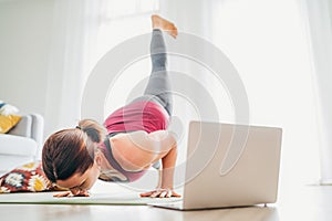 Fit sporty healthy woman on mat in Four-Limbed Staff Eka Pada Chaturanga Dandasana pose, doing breathing exercises, watching