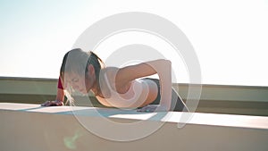 Fit sporty woman doing plank outdoors. Muscular female sport outfit doing workout. Evening footage at the sunset on