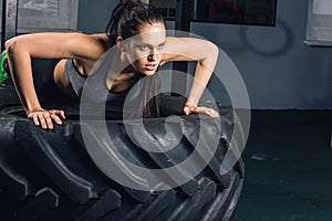 Fit sporty woman doing push ups on tire strength power training concept