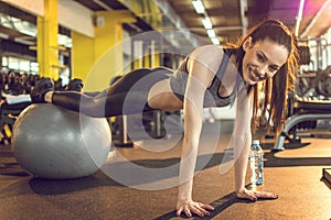 Fit sporty woman exercising on fitness ball at gym