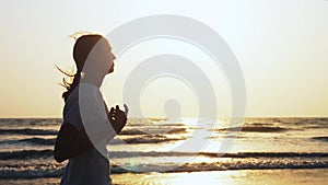 Fit sporty woman is jogging on the beach at sunset