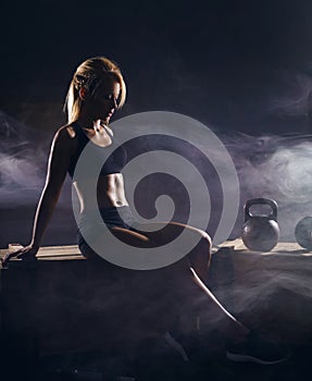 Fit and sporty young girl having a training. Dark underground gym. Health, sport, fitness concept.