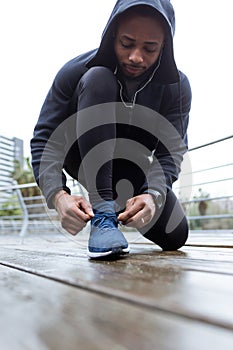 Fit and sporty young man tying her laces before a run in the cit