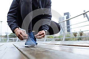 Fit and sporty young man tying her laces before a run in the cit