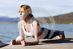 Fit and sporty young woman doing stretching next to the lake.