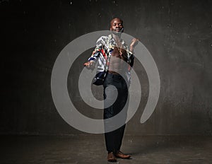 Fit strong physique African American young man wearing black hat and trousers posing dancing