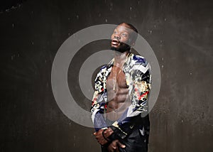 Fit strong physique African American young man wearing black hat and trousers posing dancing