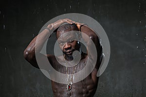 Fit strong physique African American young man wearing black hat and trousers posing dancing