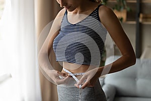 Fit strong young woman measuring waist with tape.