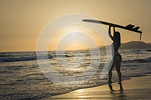 Fit surfgirl on the beach at sunset