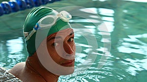 Fit swimmer smiling up at camera in the swimming pool