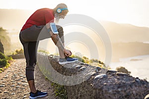 Fit tattoo man tie his sport shoes outdoor during jogging session - Workout and fitness lifestyle concept - Focus on hands