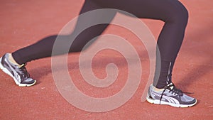 Fit teen girl wearing black sportswear in a red gym space doing long lunge cardio exercise