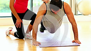 Fit toned man doing pressups in fitness hall